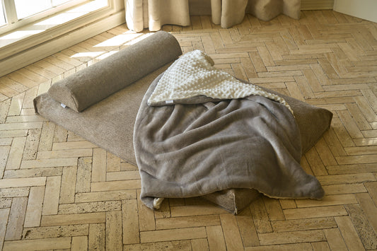 Comfort blanket laid across sofa; gray throw with white bumpy panel folded on top