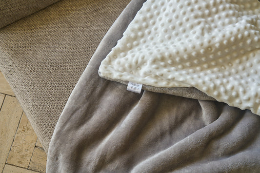 Close-up of comfort blanket corner: gray fabric with white textured dots and label