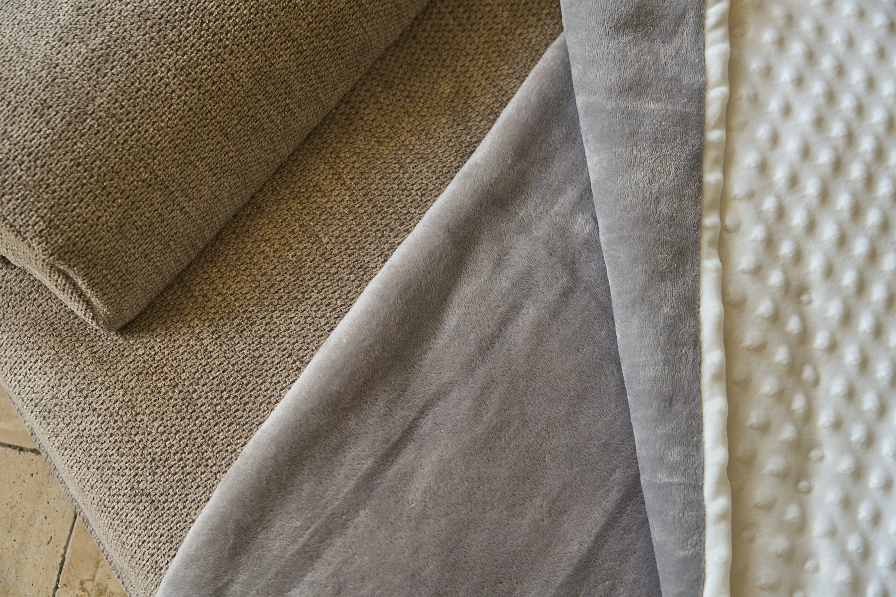 Close-up comfort blanket edge over sofa: gray fabric with white bumpy trim