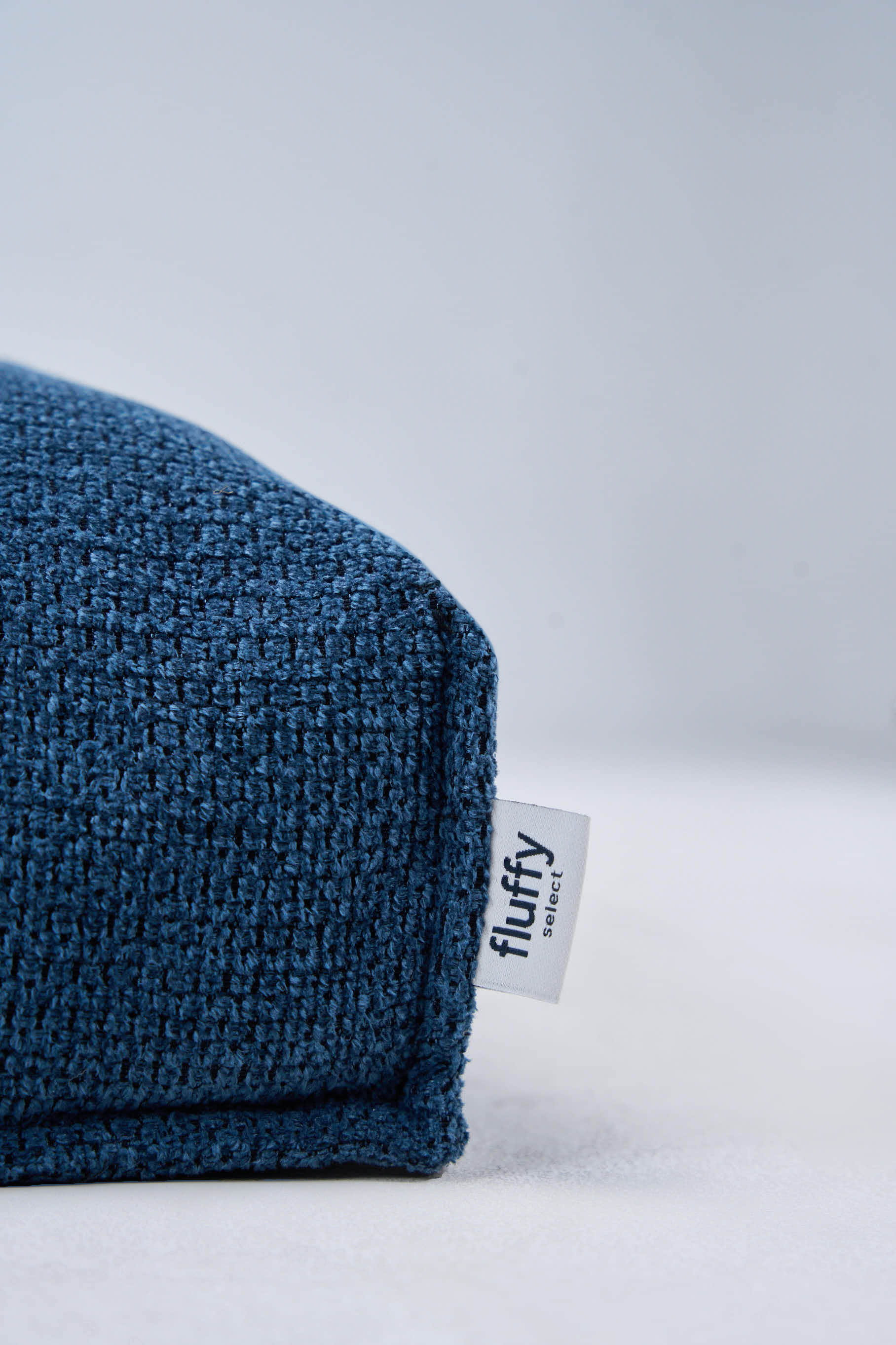 Blue textured dog bed corner with visible Fluffy tag