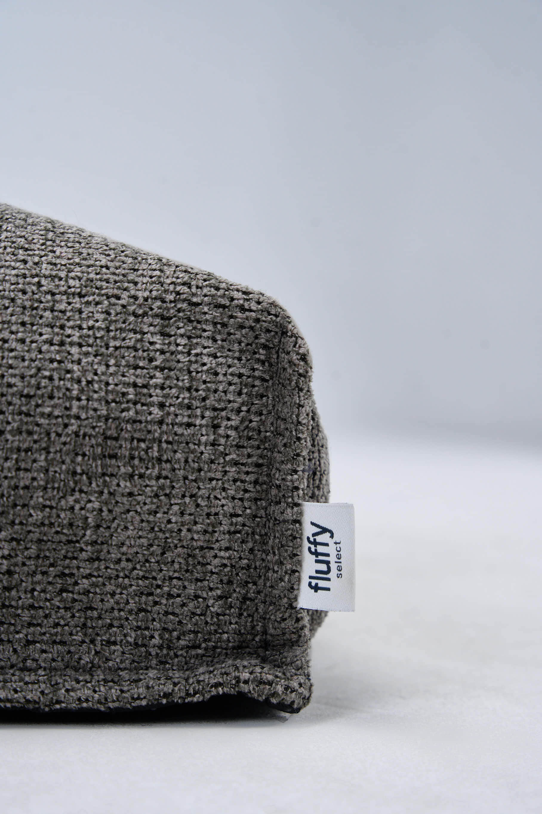 Dark gray textured dog bed cushion with Fluffy tag on the side