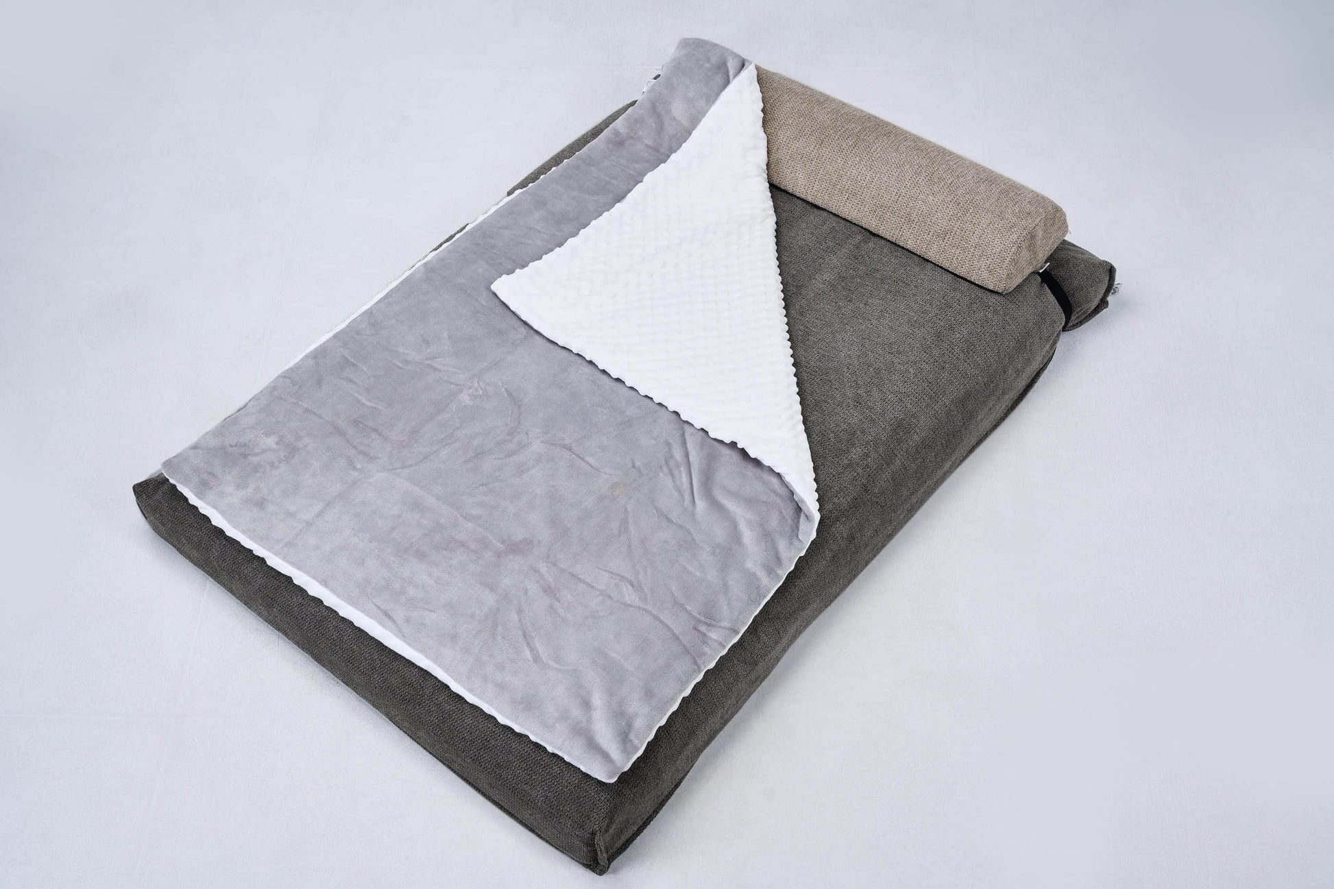 AirNest pillow with anthracite-gray cover and two folded top layers, white fabric lining