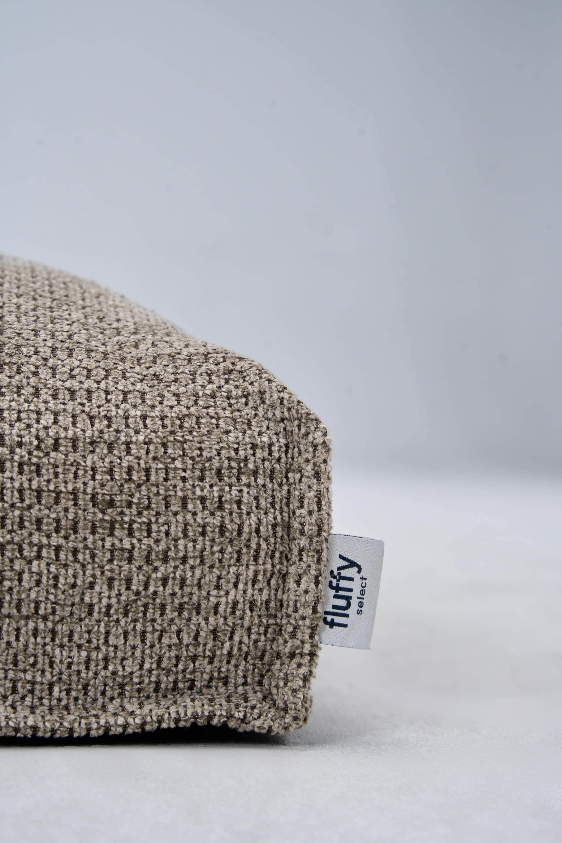 Light gray dog bed cushion corner with visible Fluffy tag