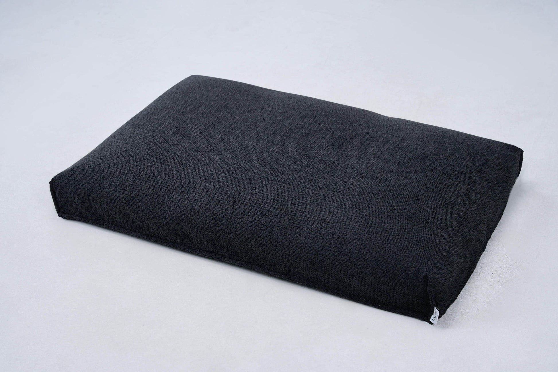 AirNest dog bed cushion in dark charcoal/black fabric with corner ties