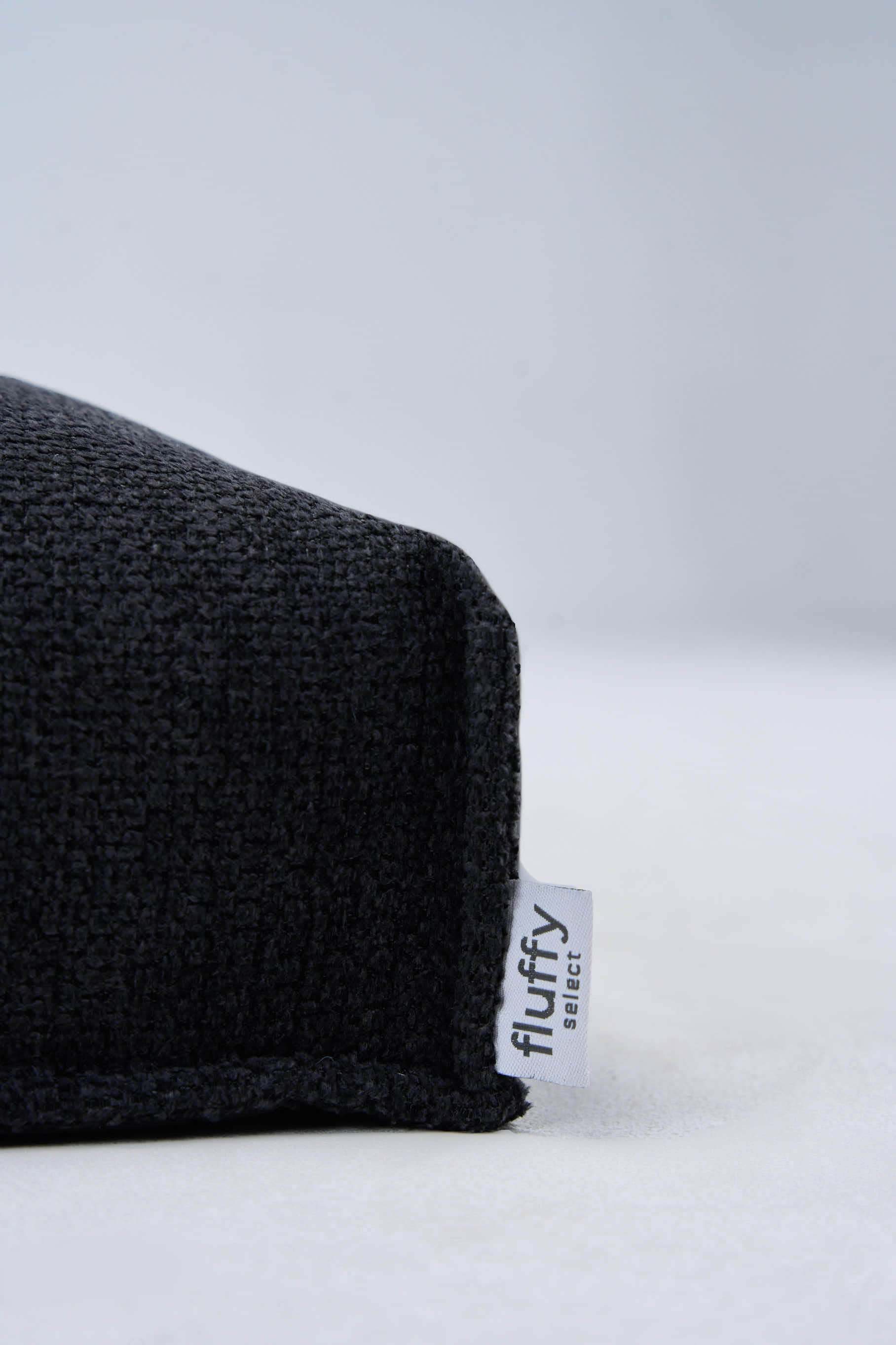 Dark gray dog bed corner with visible Fluffy fabric tag