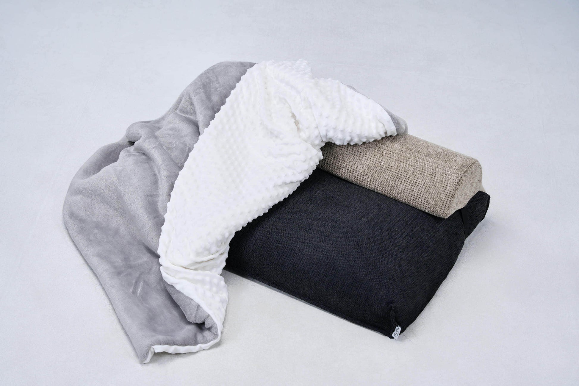 Comfort blanket stack with taupe and dark gray sides, plus white bumpy trim edge