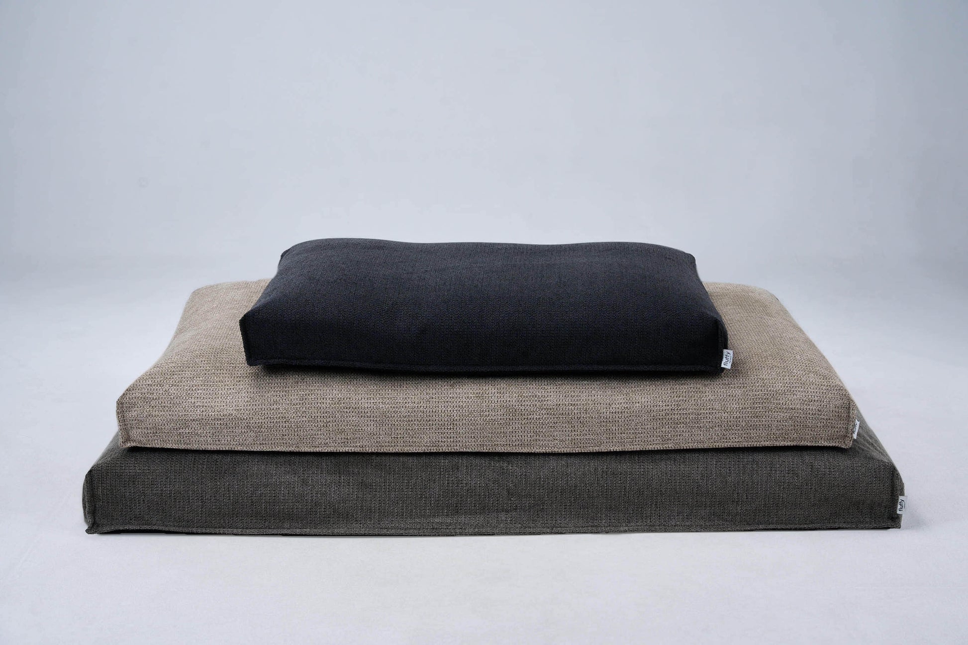 Dog bed stack with beige base and dark top cushion; sewn edge detail
