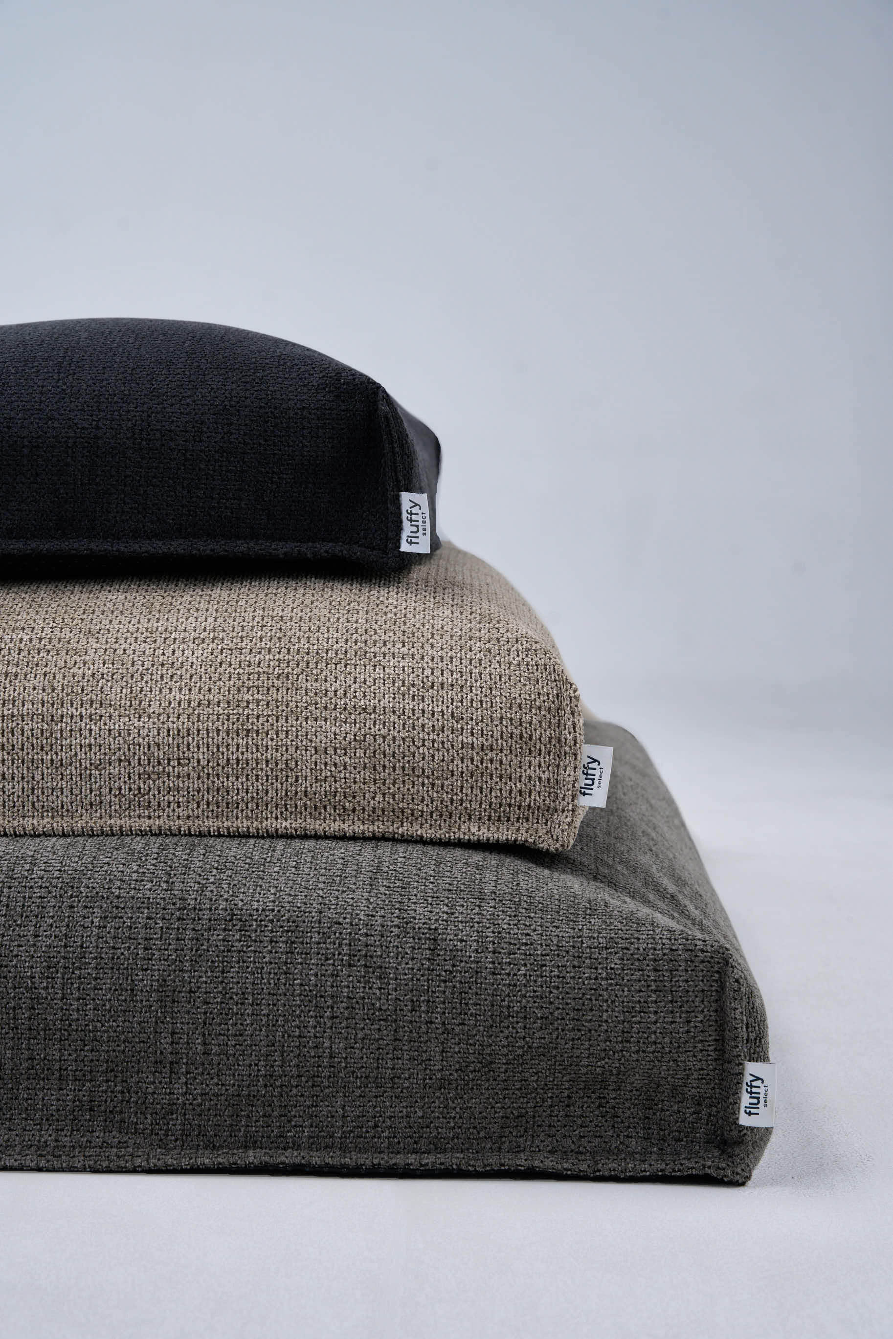Dog bed with textured dark cover and beige base; label tags visible